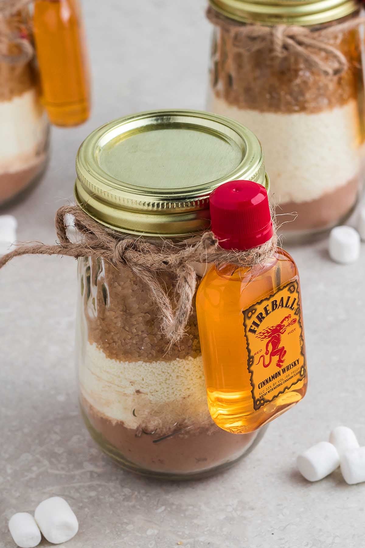 A mason jar hot chocolate gift kit with a bottle of bourbon.