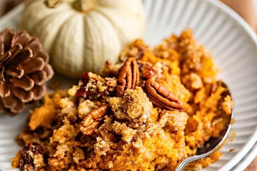 A plate of sweet potato casserole with pecans over the top.