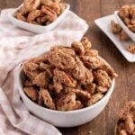 Bowls brimming with delicious candied pecans rest on a wooden table, perfectly accented by a cozy checkered cloth.
