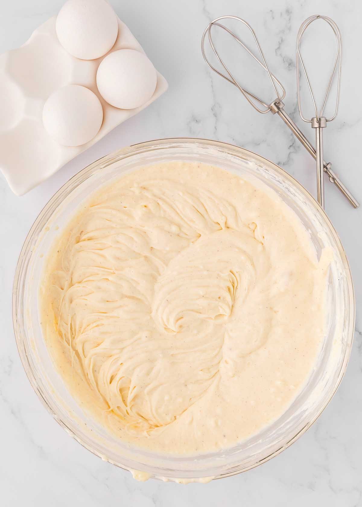 A bowl with eggs and a whisk next to it, perfect for making eggnog cheesecake with a gingersnap crust.
