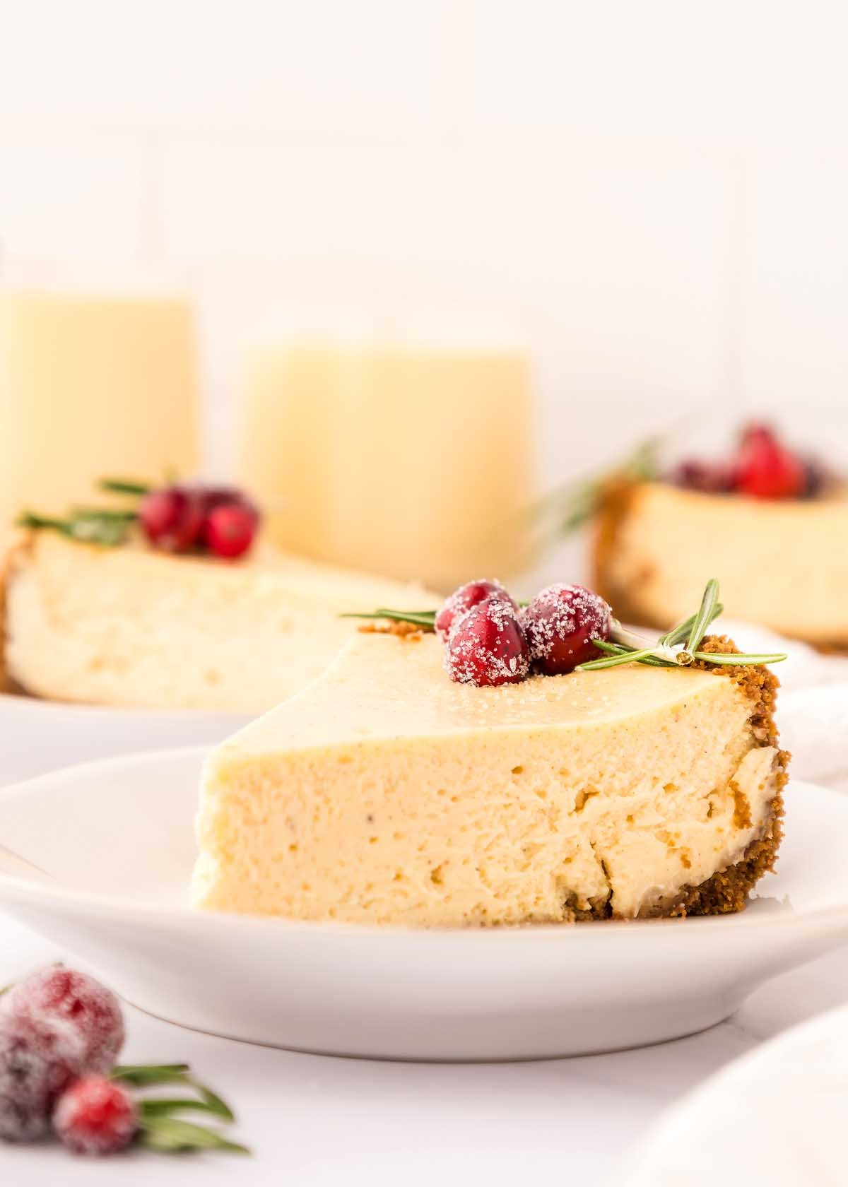 A festive slice of eggnog cheesecake with cranberries on a plate.