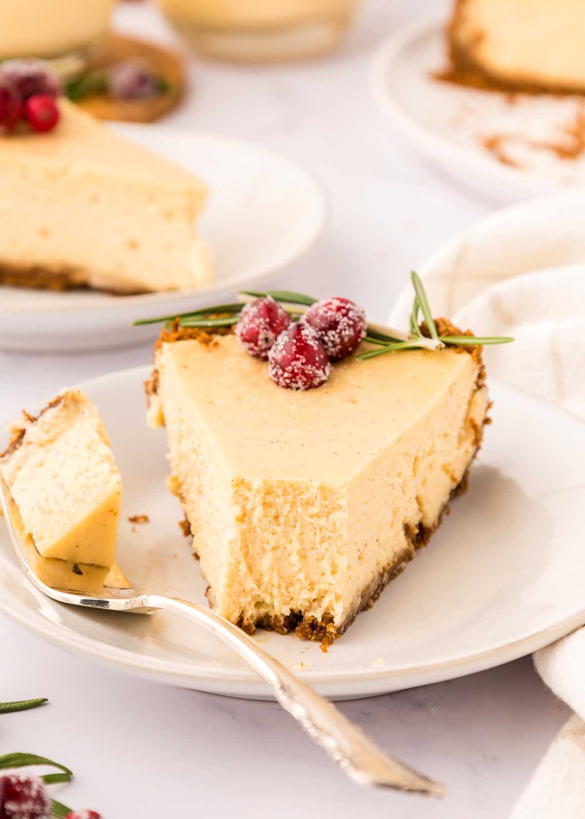 A festive slice of eggnog cheesecake with cranberries on a plate.