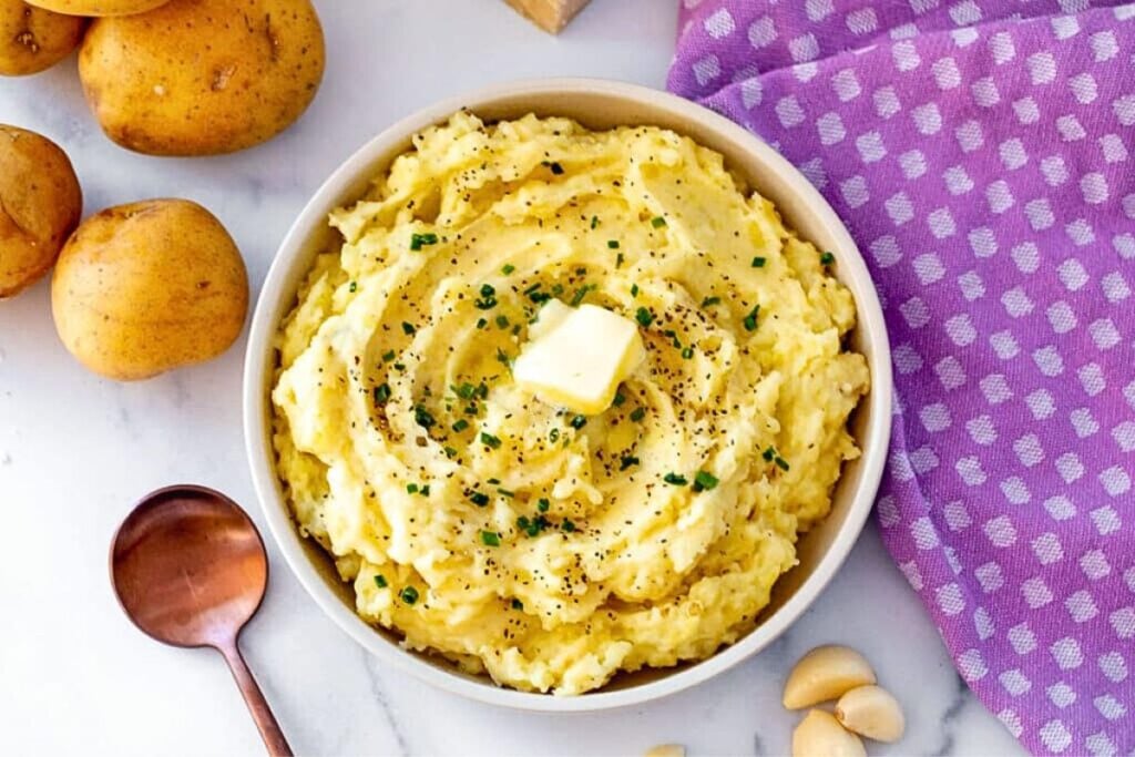 A bowl of garlic parmesan potatoes with a large pat of melting butter in the middle.