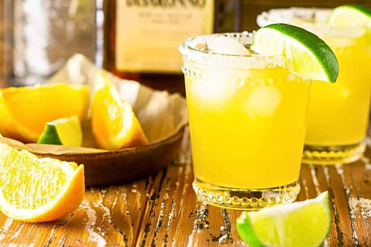 An Italian margarita with lemon and lime wedges.