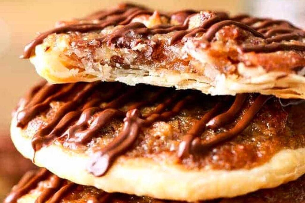 A stack of nutty pecan doughnuts with chocolate drizzle.
