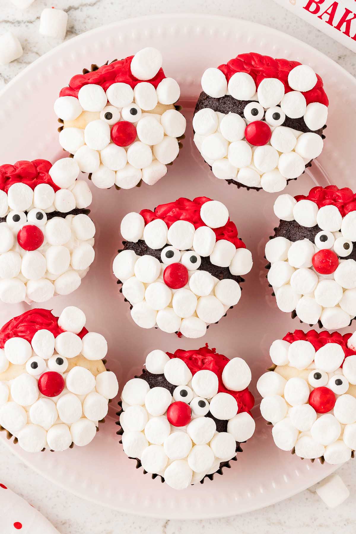 Santa face cupcakes with marshmallows on a plate.