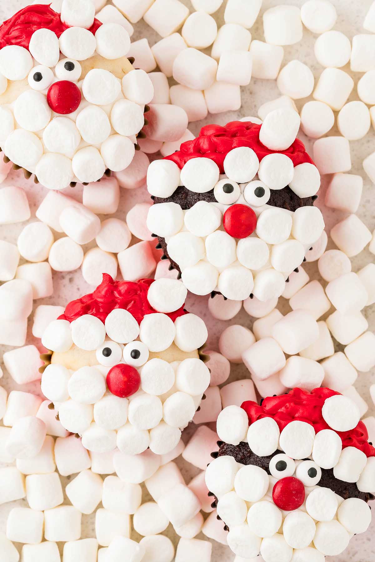 Santa-themed Christmas cupcakes adorned with marshmallows and Santa Claus faces.