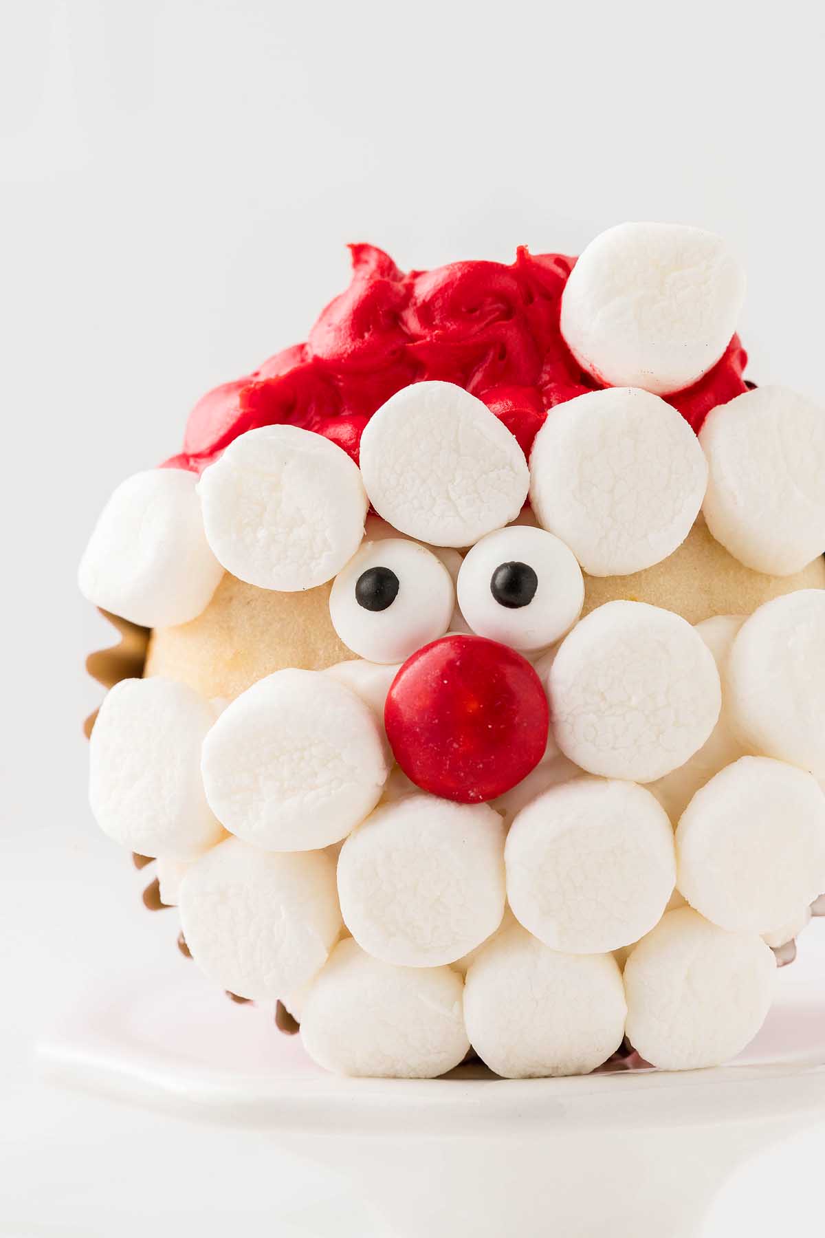 A cupcake decorated like Santa's face, with marshmallows on top.