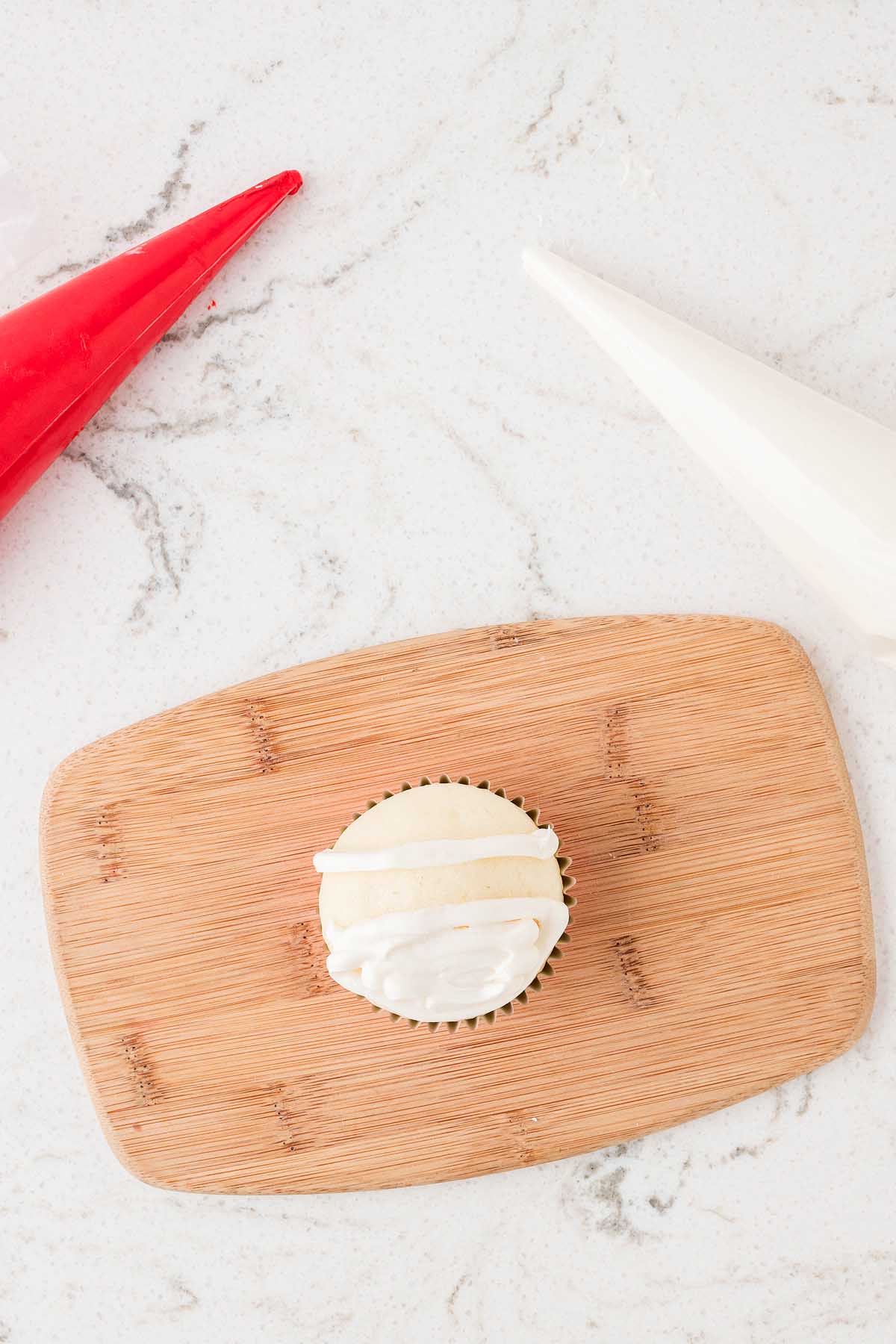 A Santa cupcake on a wooden cutting board surrounded by red and white cones.