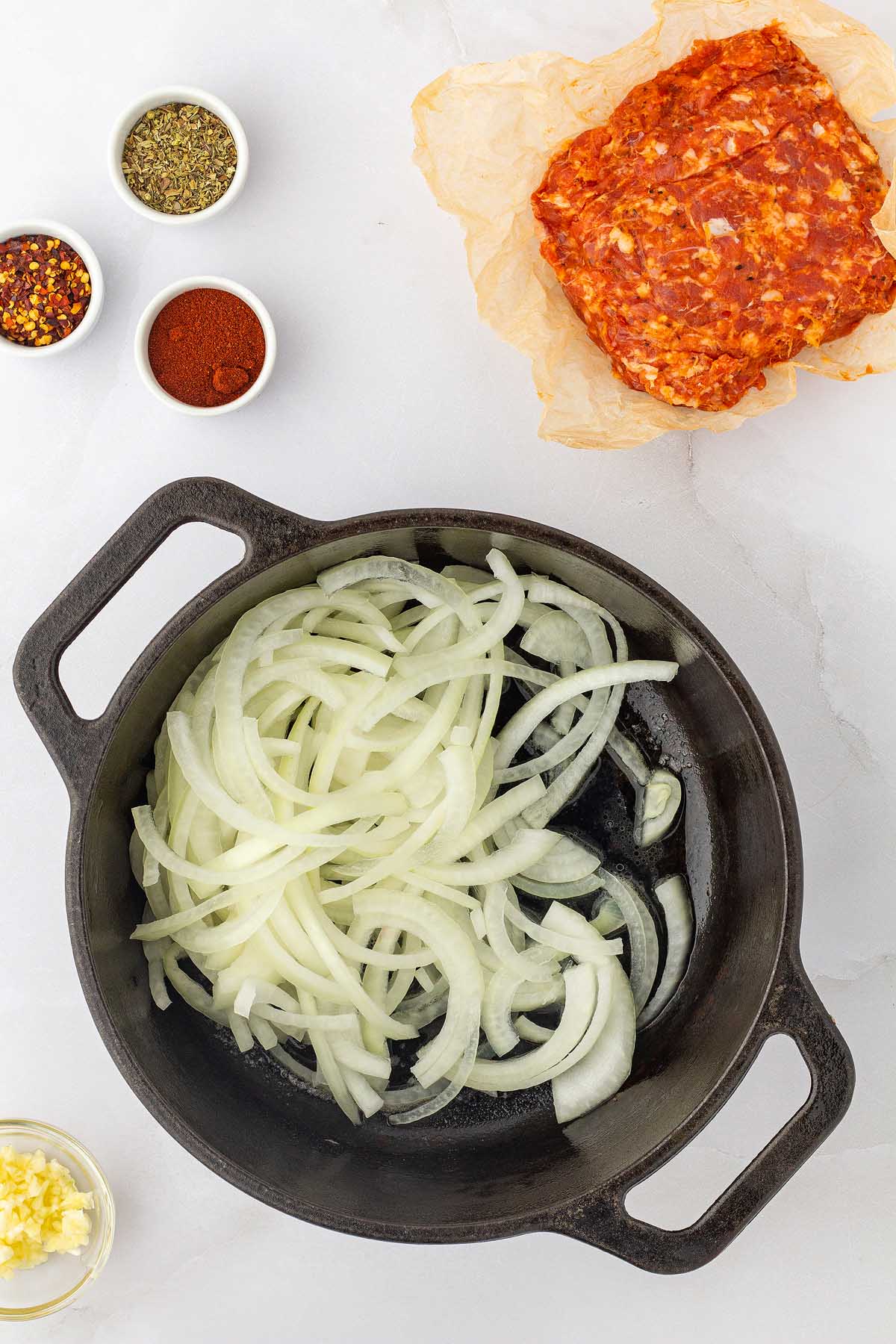 A cast iron skillet with Italian sausage and onions next to it.