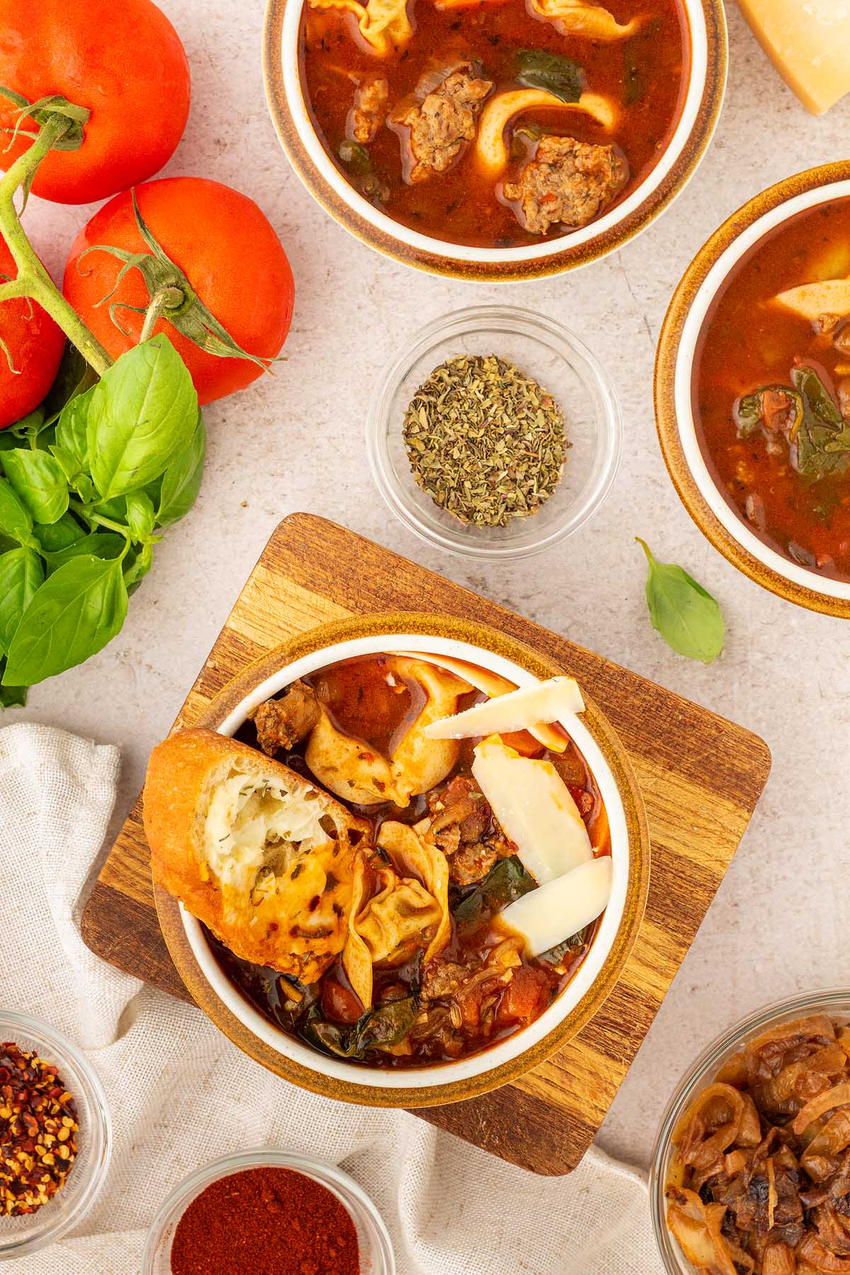 Several bowls of sausage tortellini soup are on a table.