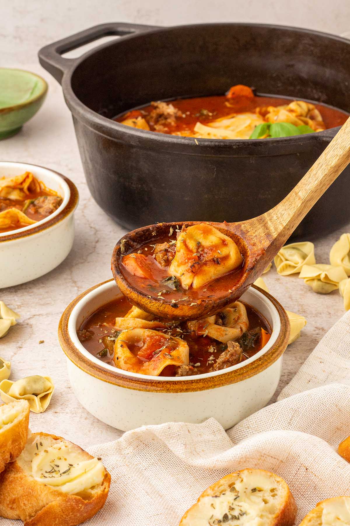 Creamy sausage tortellini soup in a pot served with bread.