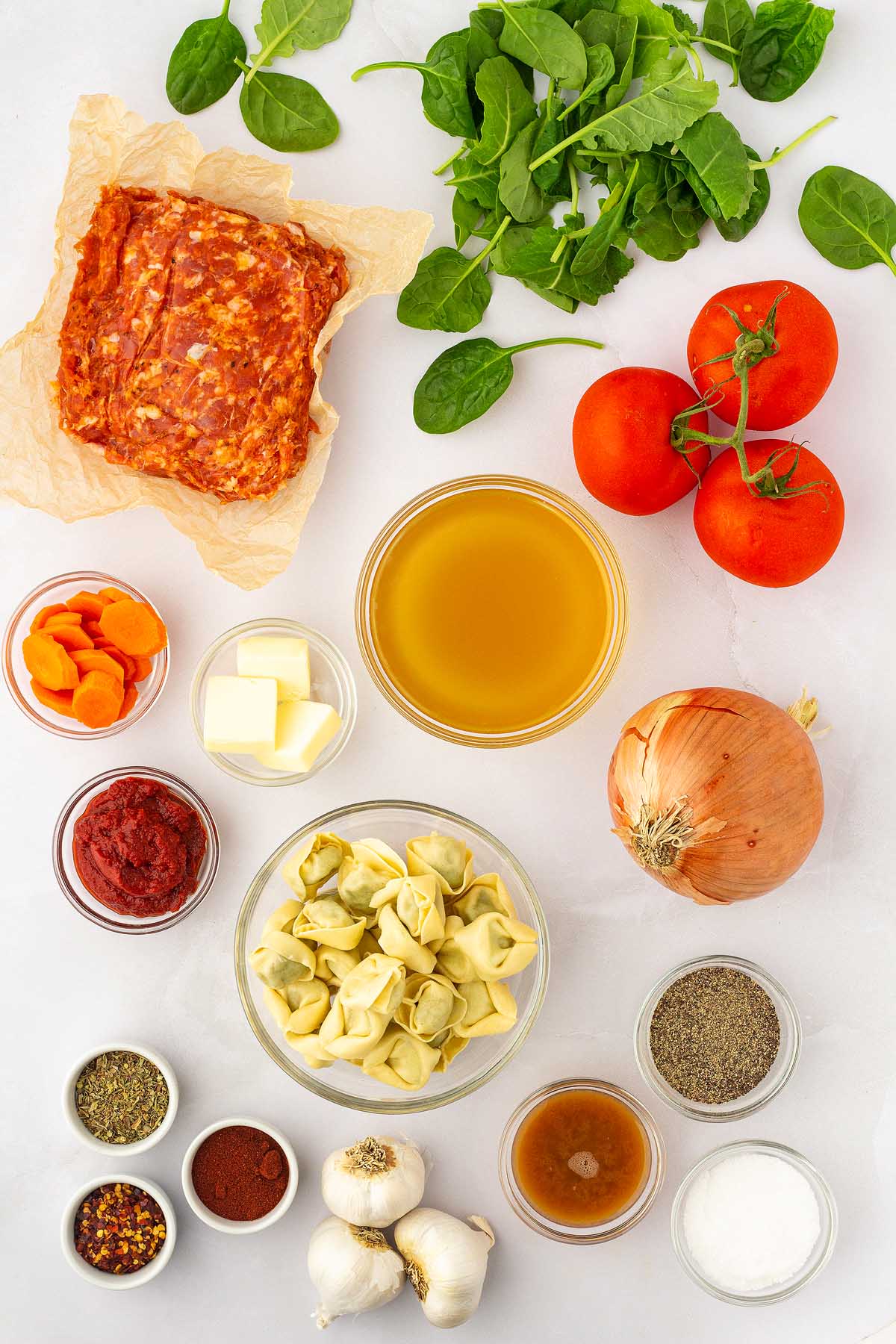 The ingredients for an Italian sausage  are tortellini laid out on a white surface.