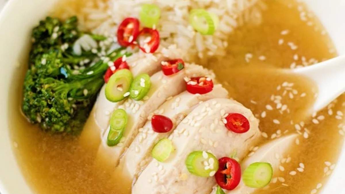 A bowl of chicken soup with rice and broccoli.