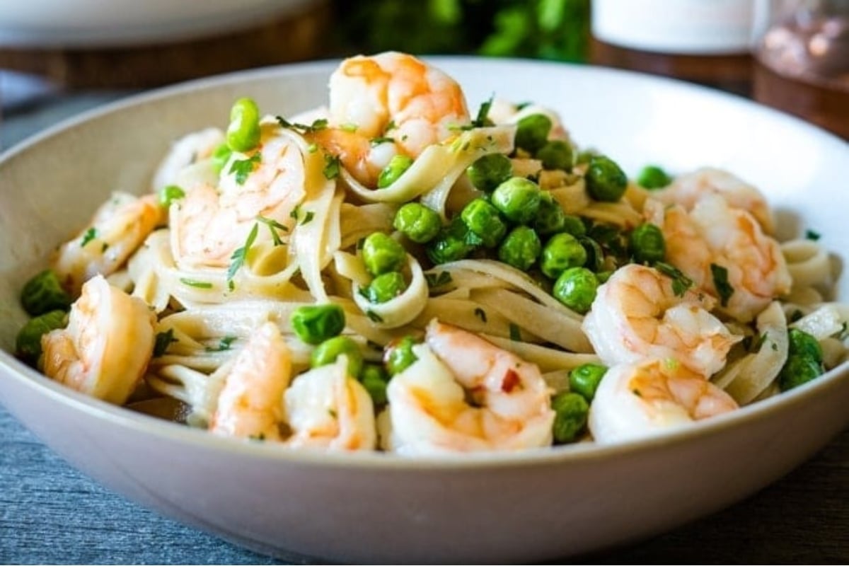 A feast of seven fishes featuring a bowl of pasta with shrimp and peas.