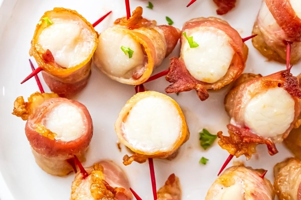 Bacon wrapped appetizers on a white plate, perfect for New Year's dinners.