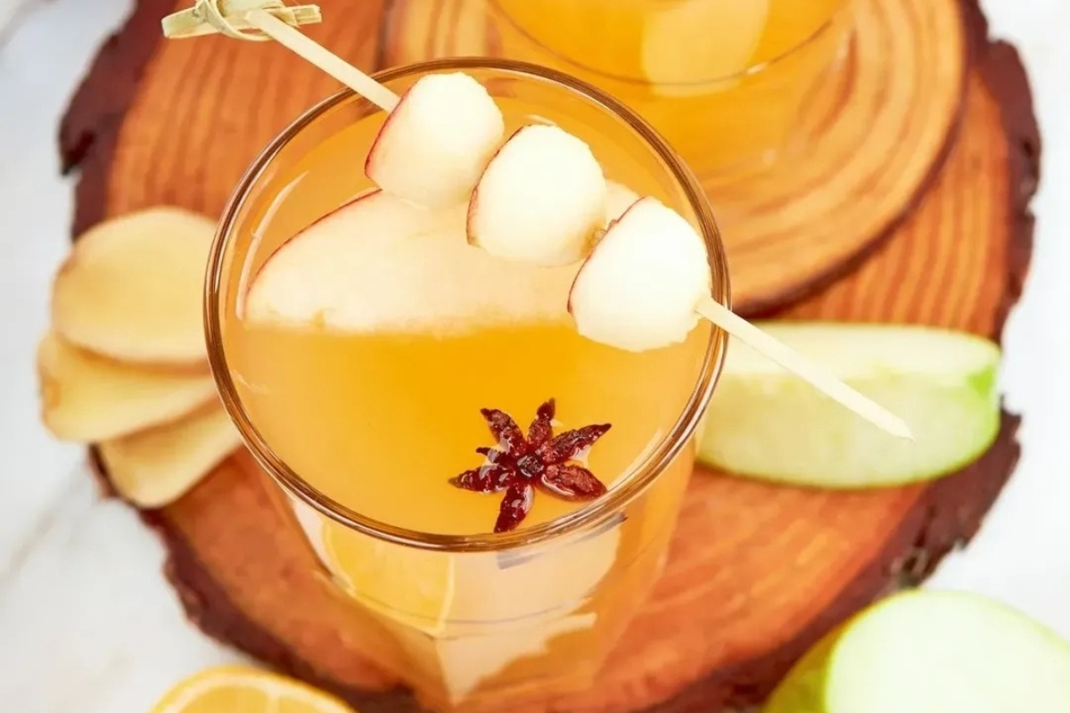 A festive glass of apple cider adorned with cinnamon sticks and apple slices, perfect for a memorable New Year's Eve party.