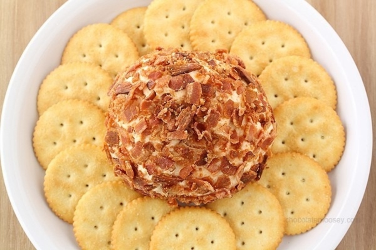 Perfect for a New Year's eve party, enjoy a savory bacon cheese ball served on a white plate with accompanying crunchy crackers.