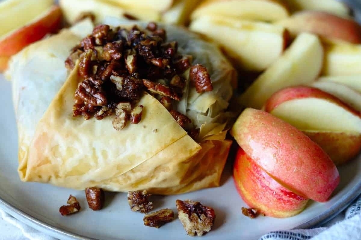 A plate of appetizers with apples and pecans on it, perfect for a NYE celebration.