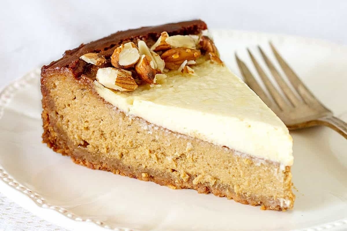 A festive slice of pumpkin cheesecake on a plate with a fork, perfect for holiday gatherings.