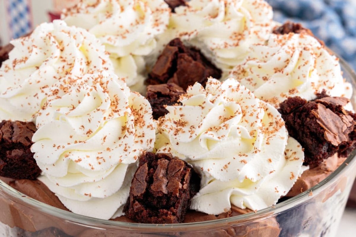 Christmas chocolate brownie trifle in a glass bowl with whipped cream.