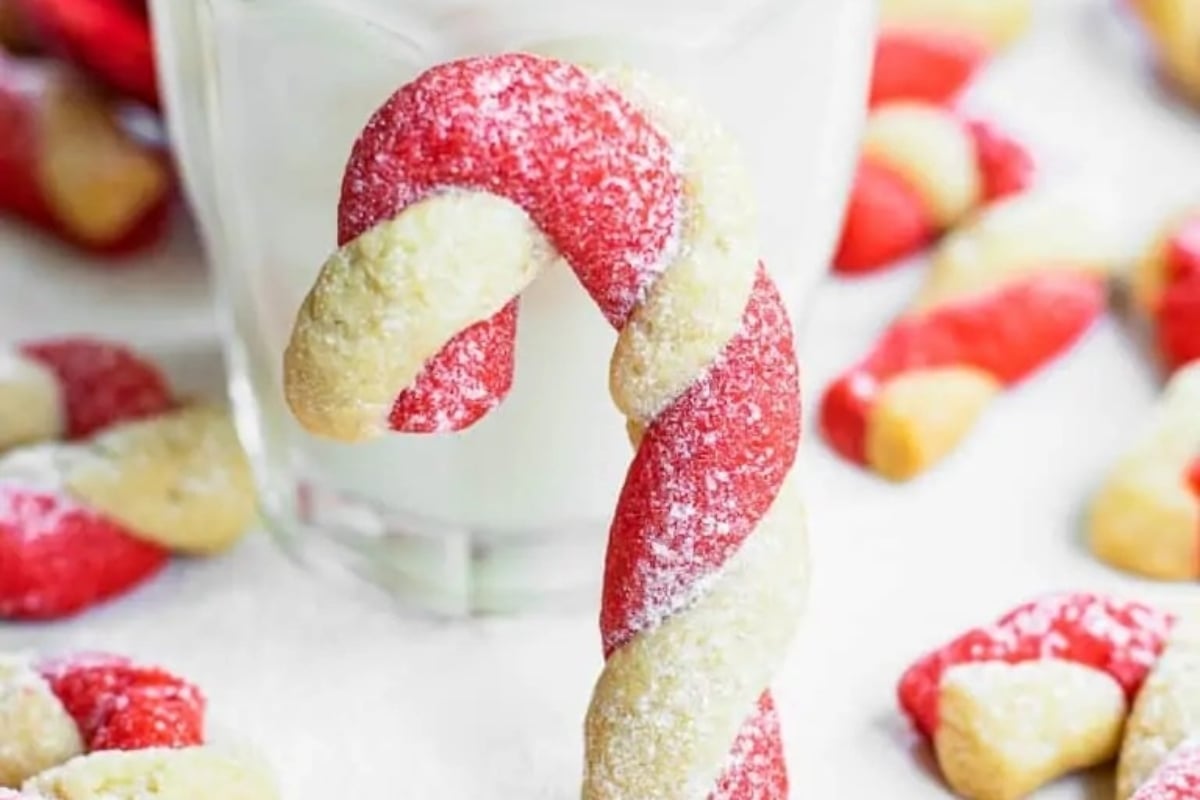 Candy cane cookies next to a glass of milk, a perfect treat for the holiday season.