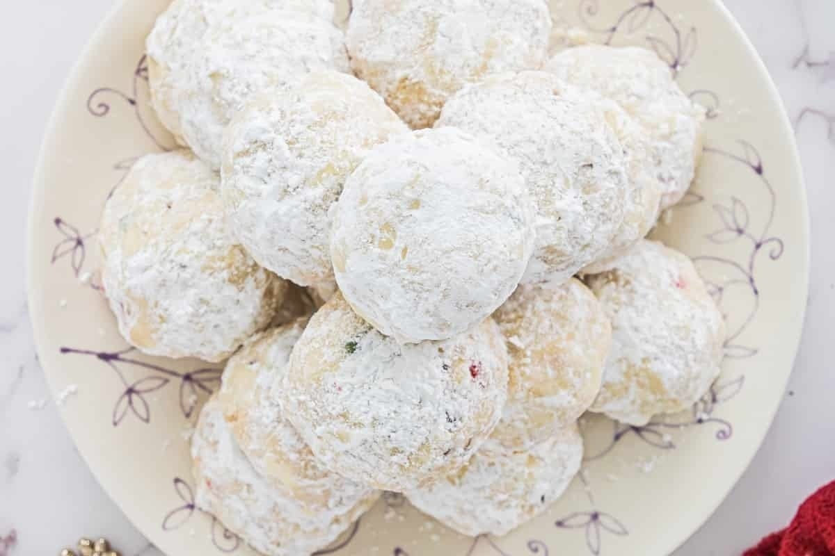 Powdered sugar cookies with a candy cane twist, beautifully arranged on a plate.