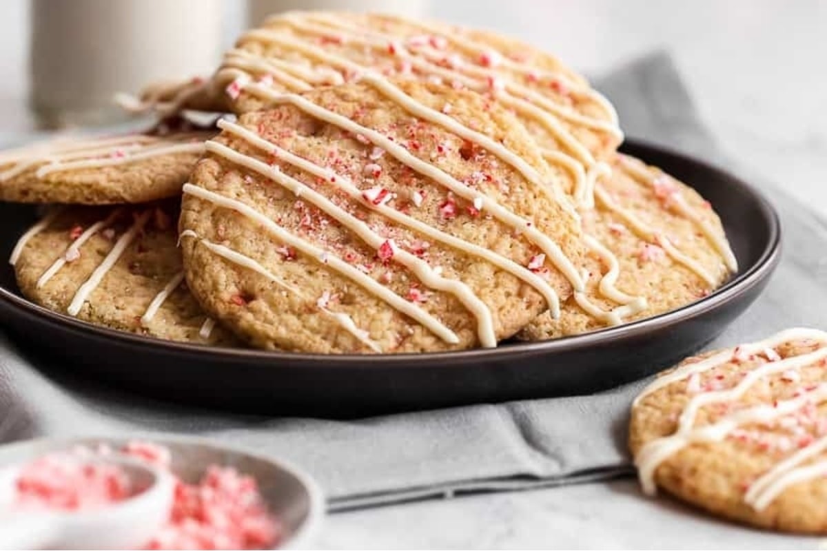 A plate of cookies with icing and peppermint sprinkles, perfect for candy cane lovers.