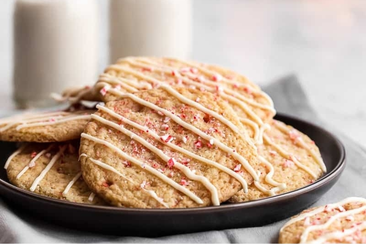 A plate of peppermint cookies with icing and a glass of milk.