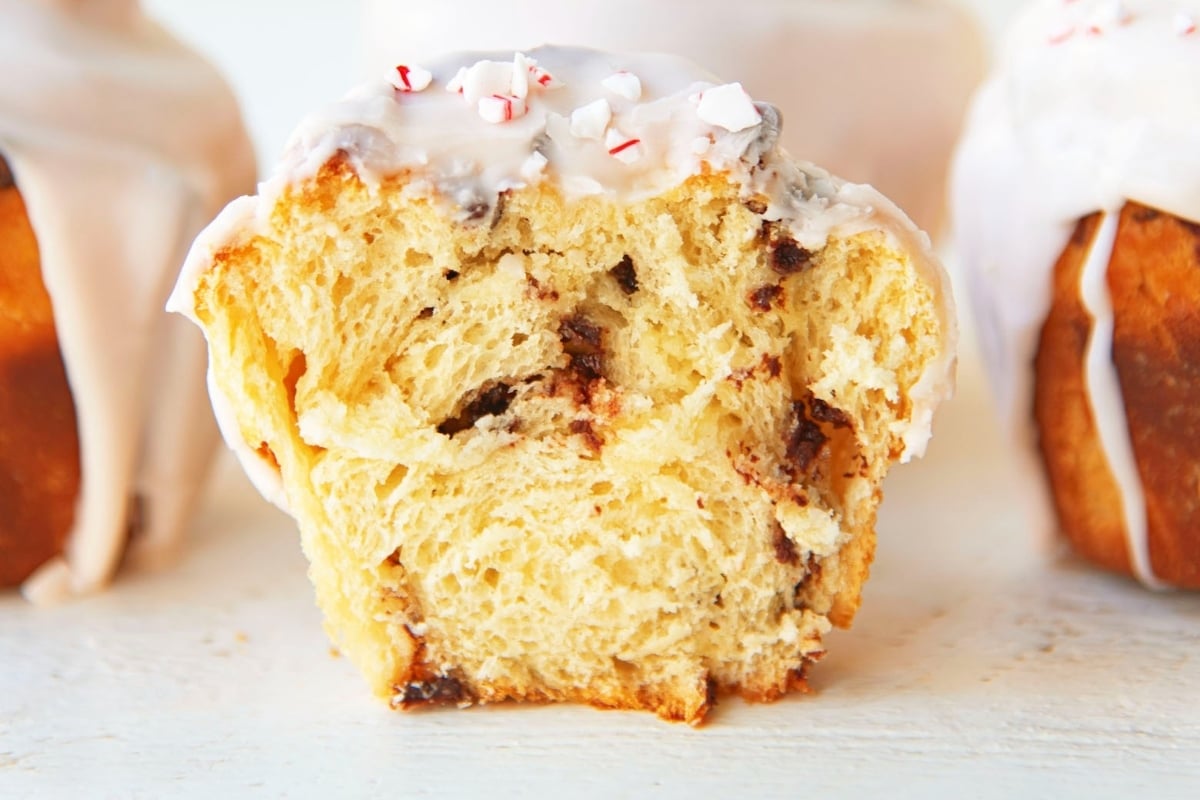A close up of a muffin with icing and peppermint sprinkles, perfect for those who love candy cane recipes.
