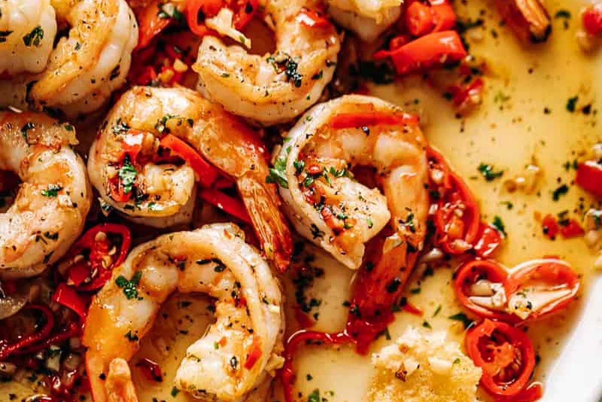 A feast of seven fishes spread out on a white plate, featuring shrimp and peppers as standout delicacies.