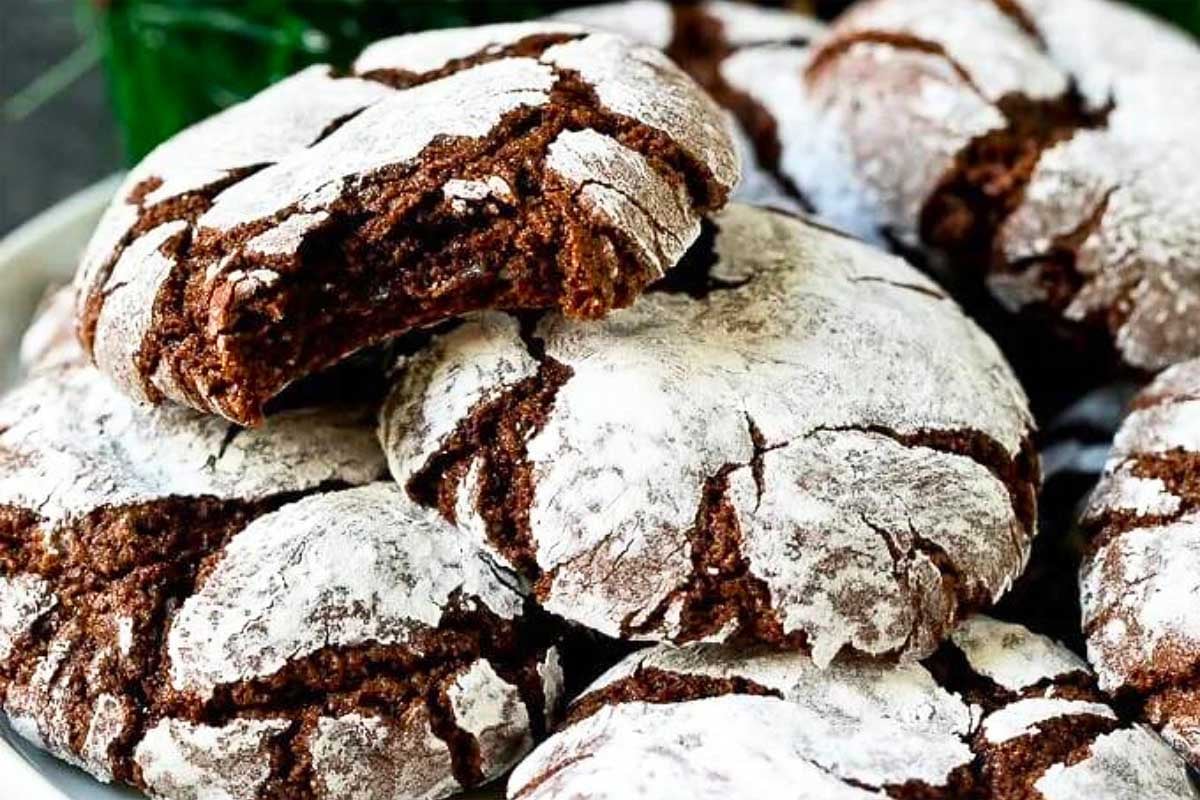 Chocolate crinkle cookies dusted with powdered sugar on a plate.