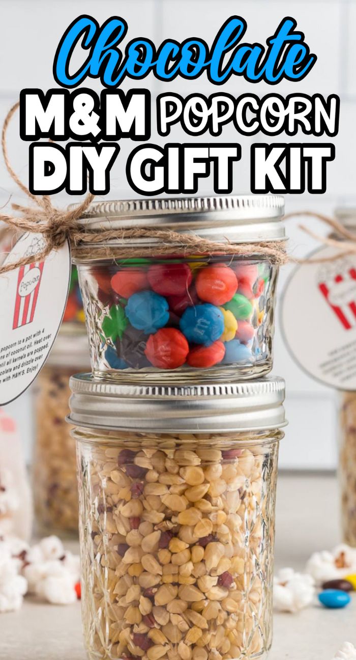 Two mason jars stacked; one holds colorful M&Ms, the other is filled with popcorn kernels—create your own Chocolate M&M Popcorn DIY Gift Kit.