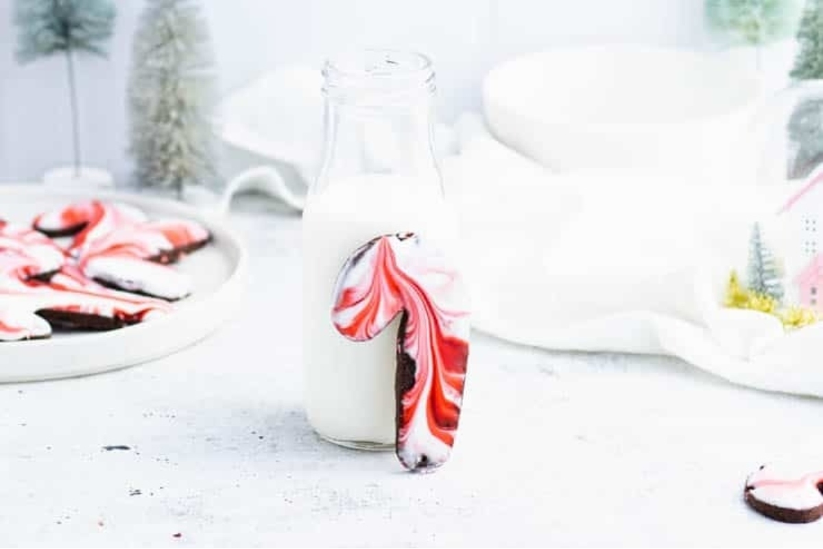A glass of milk next to a peppermint cookie.
