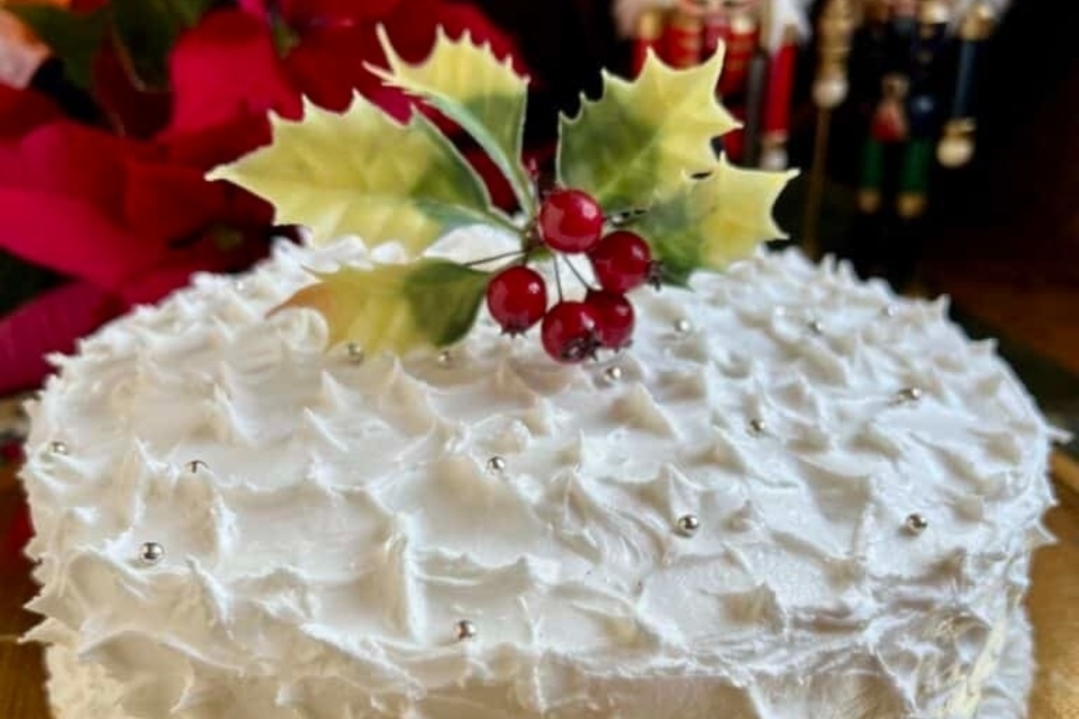 A festive white cake adorned with holly leaves, perfect for make ahead holiday dishes.