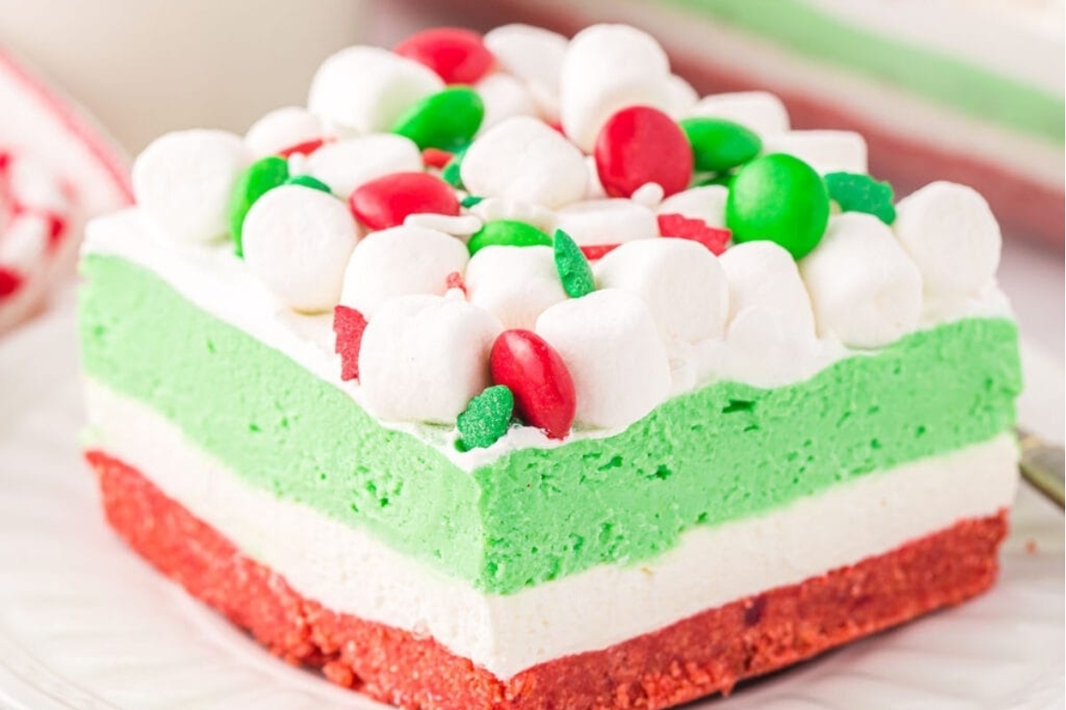 A piece of green, red and white ice cream cake on a plate.