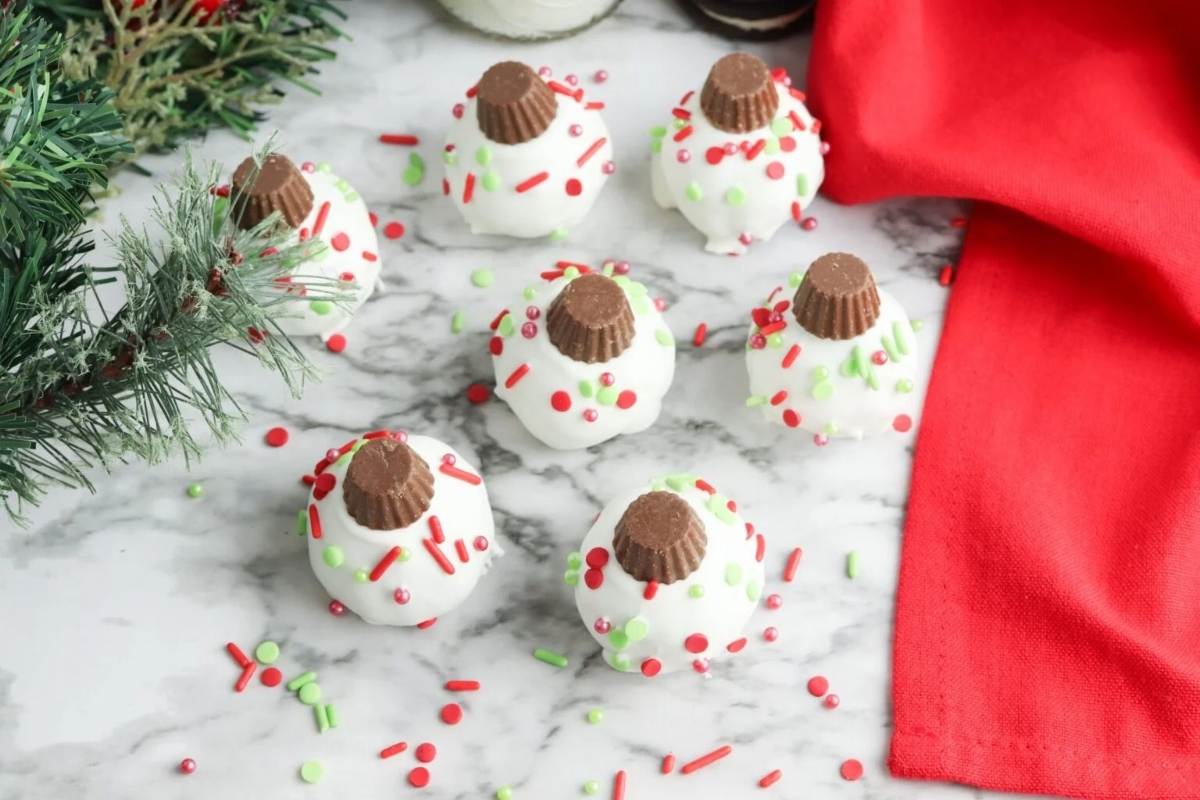 Christmas cookie balls with sprinkles on a marble table.