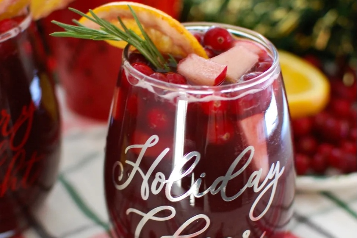 Two cranberry sangria glasses garnished with rosemary sprigs.