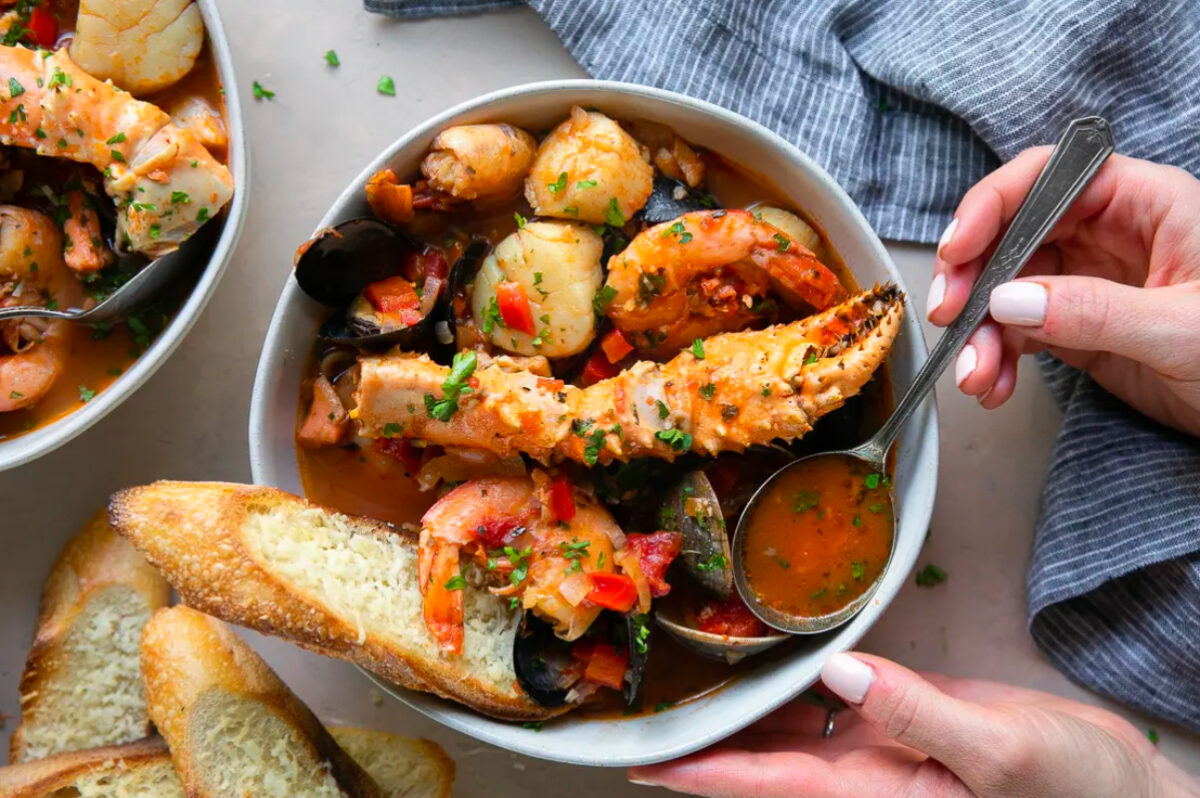 A bowl of seafood stew with potatoes and bread, perfect for festive New Year's dinners.