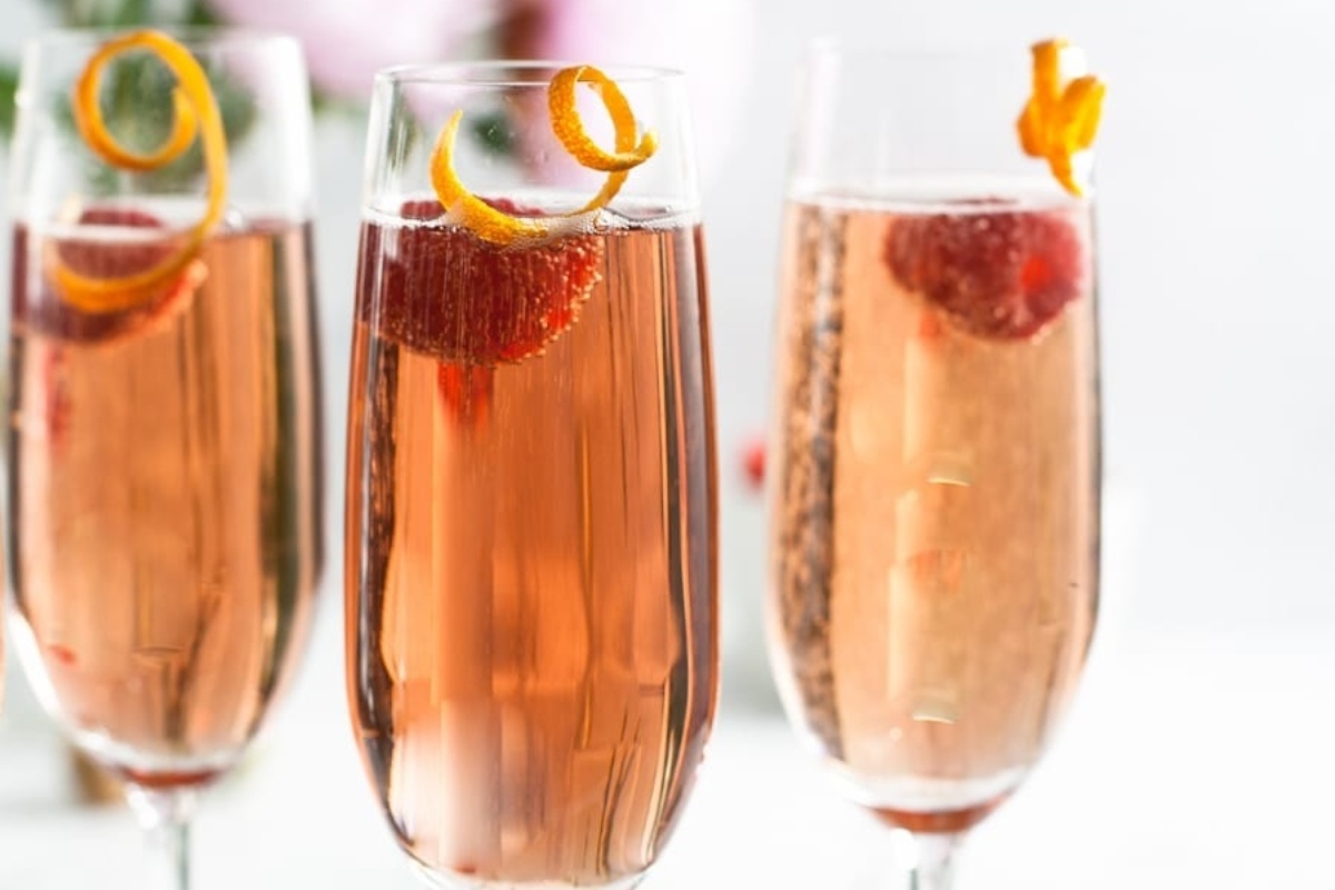 Three glasses of champagne with strawberries and oranges, perfect for New Year's Eve cocktail ideas.