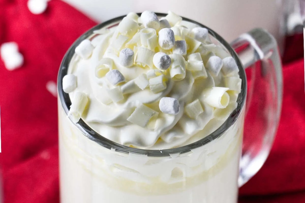 A Starbucks holiday cup of hot chocolate with marshmallows and whipped cream.