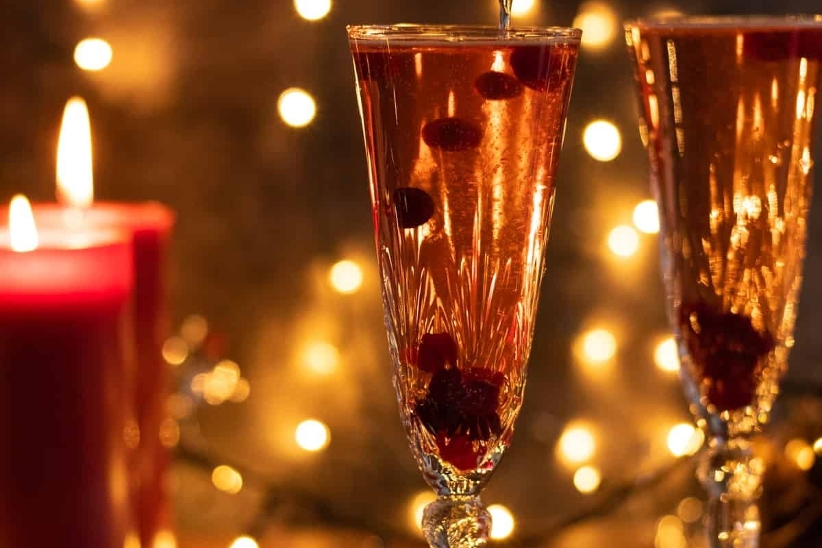 Two glasses of champagne with cranberries and candles, perfect for your New Year's eve party.