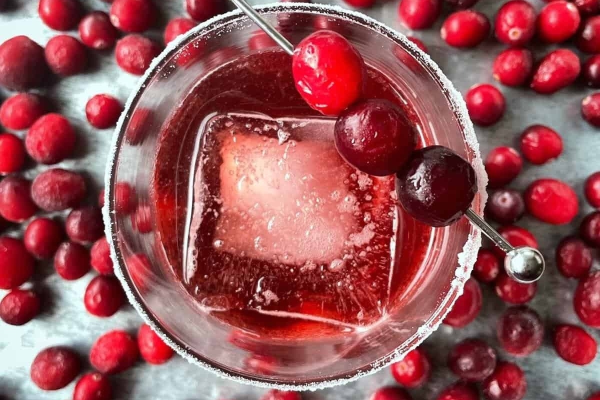 A refreshing cranberry martini garnished with ice and fresh cranberries.
