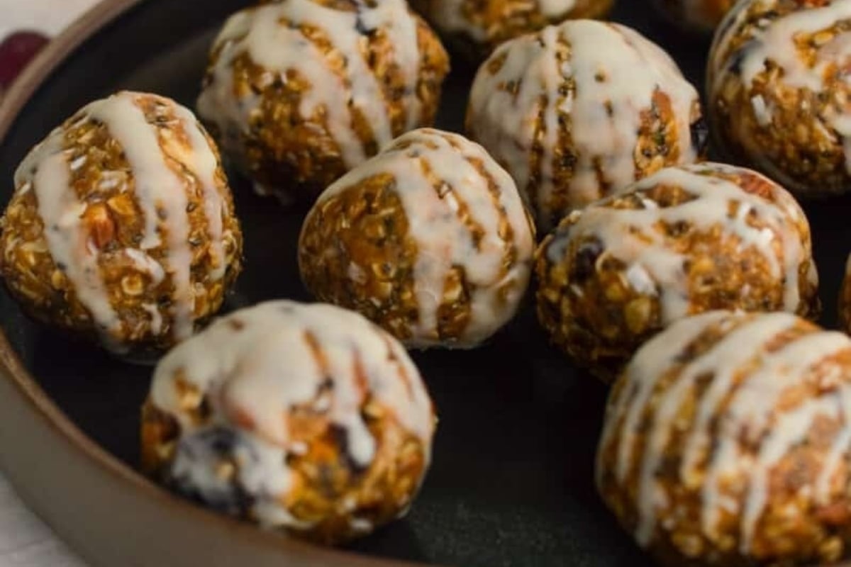 A plate full of energy balls with cranberry icing on top.