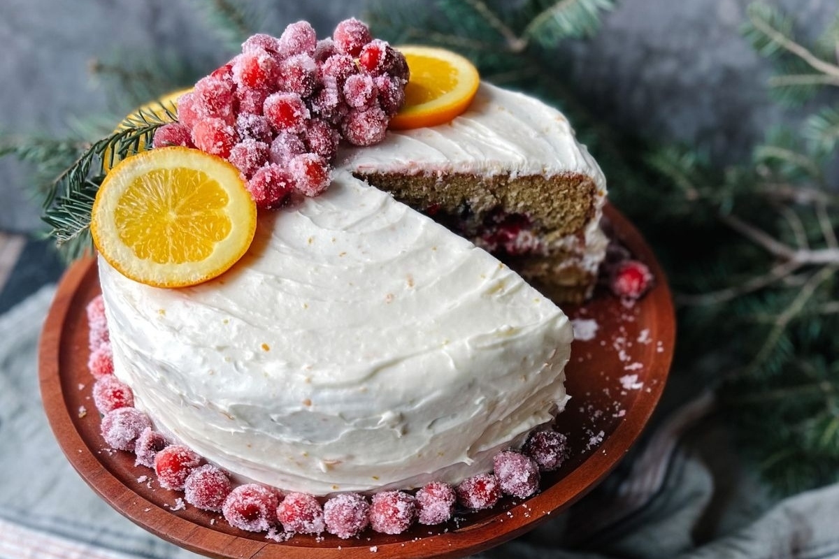 A make-ahead holiday dish, this cake features orange slices and cranberries beautifully arranged on a wooden plate.