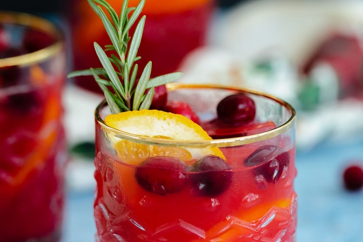 Refreshing cranberry lemonade with the zesty addition of orange slices and fragrant rosemary sprigs.