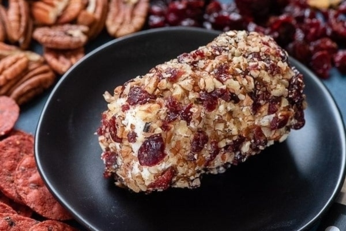 A black plate with cranberries and pecans on it, perfect for NYE appetizers.