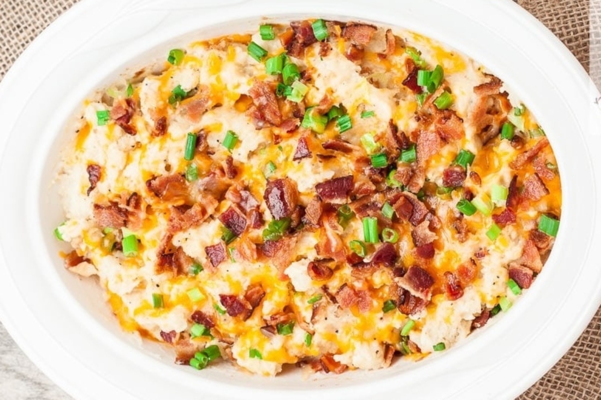 A make ahead holiday dish - a white bowl filled with a casserole with bacon and green onions.