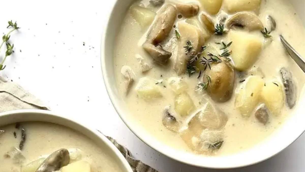 A bowl of mushroom and potato soup with sprigs of thyme.
