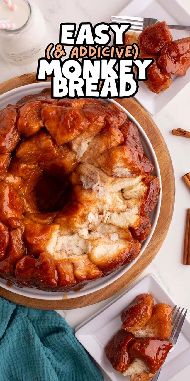 A round monkey bread on a plate with caramel glaze, served with milk and cinnamon sticks on the side.